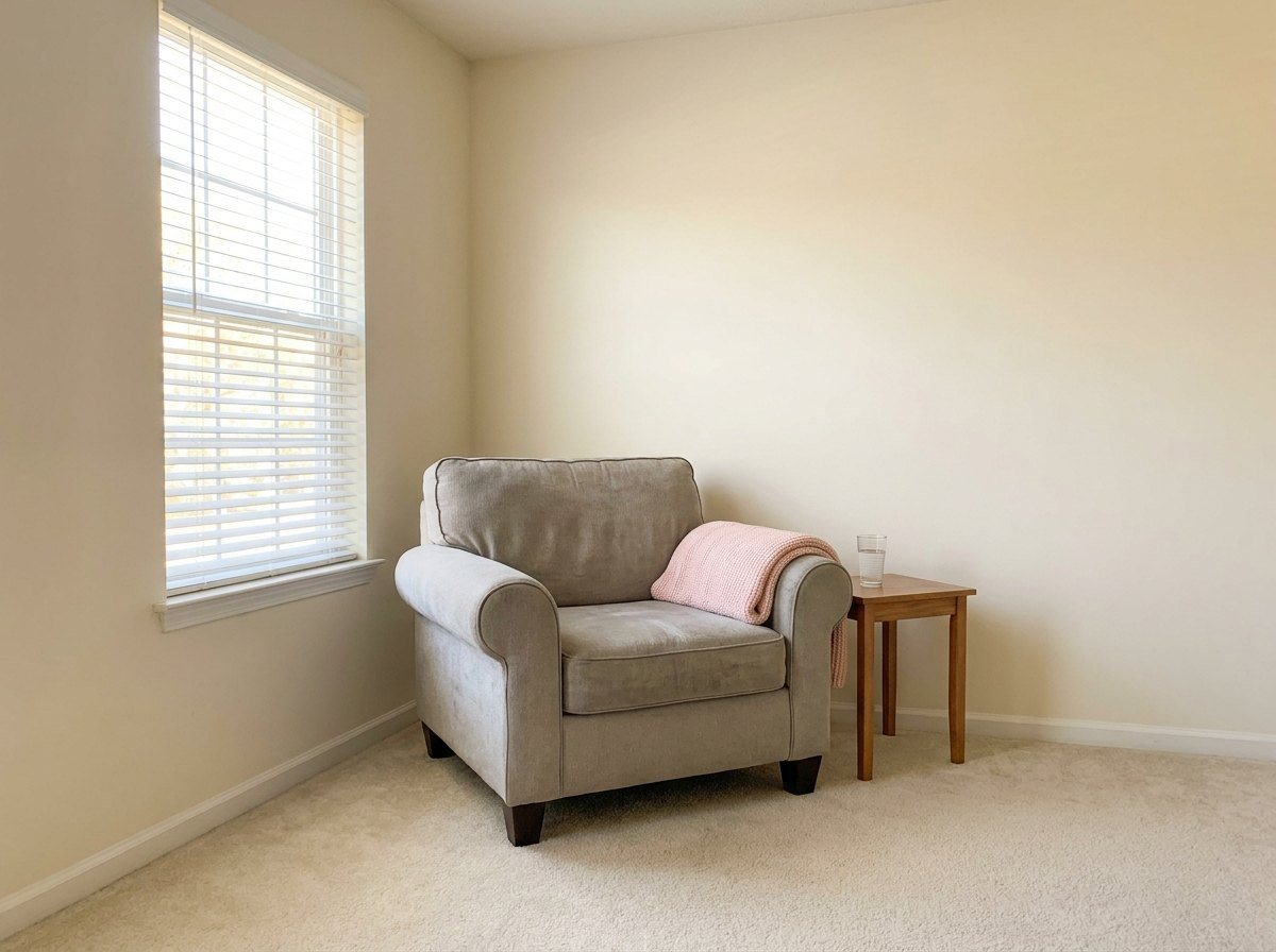 An armchair with a pink blanket beside a bright window